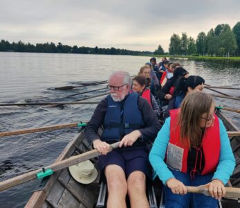 Iso aikuisryhmä soutamassa kirkkoveneellä Oulujoen suistossa.