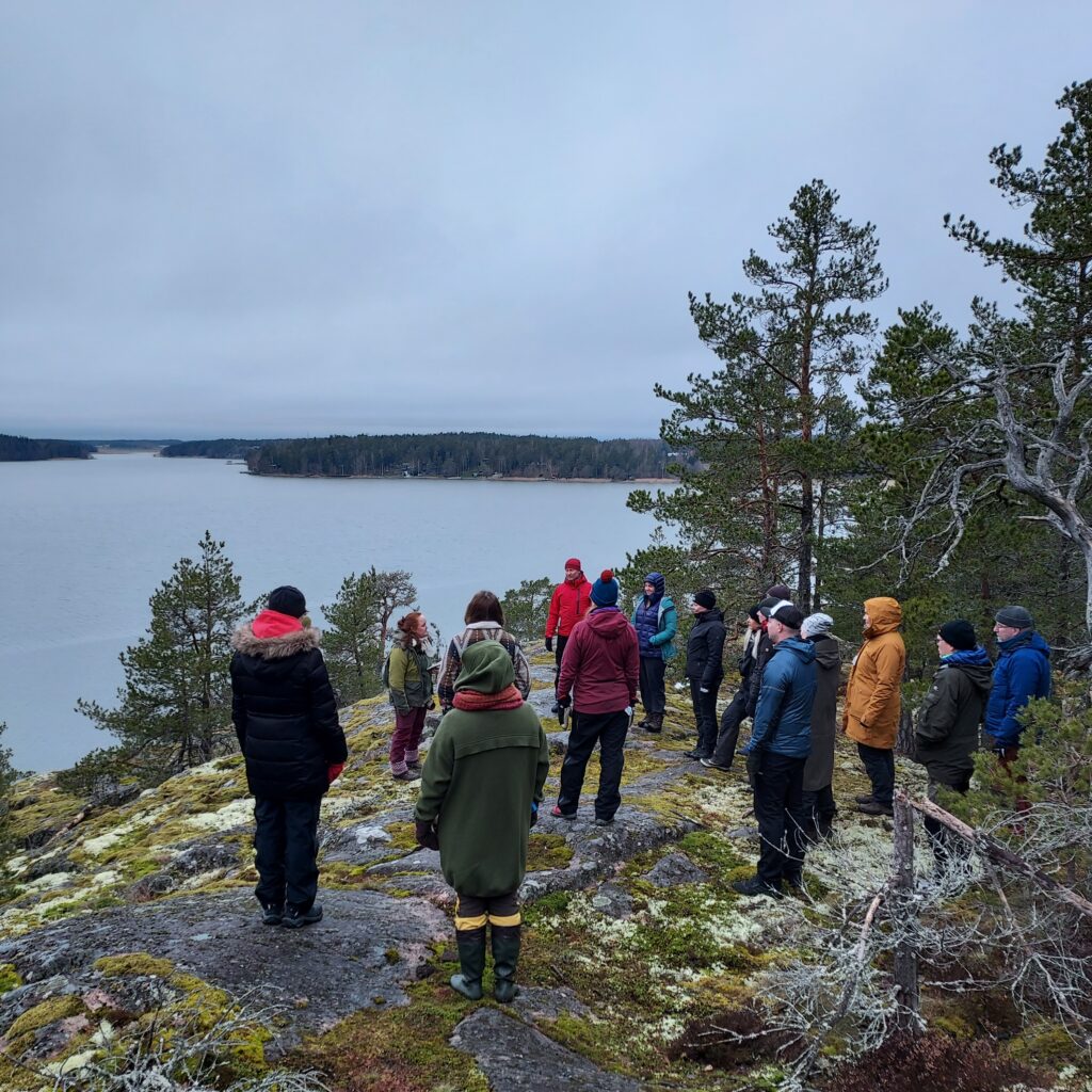 Paljon ihmisiä kalliolla veden äärellä.