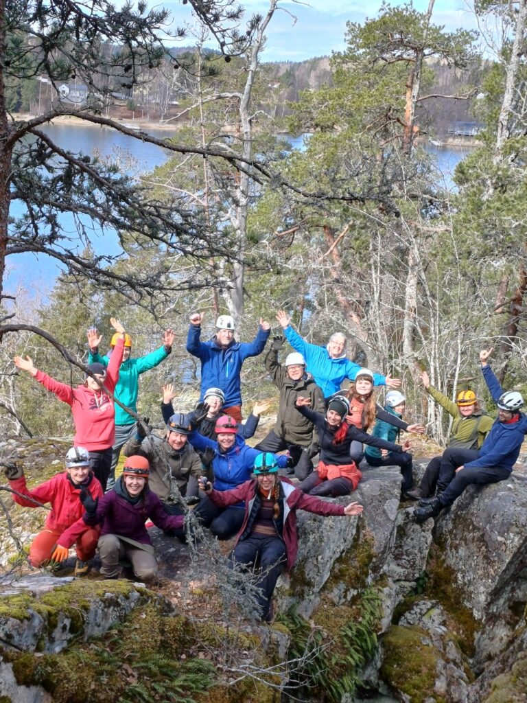 Porukkakuva luolaseikkailun jälkeen kalliolla.